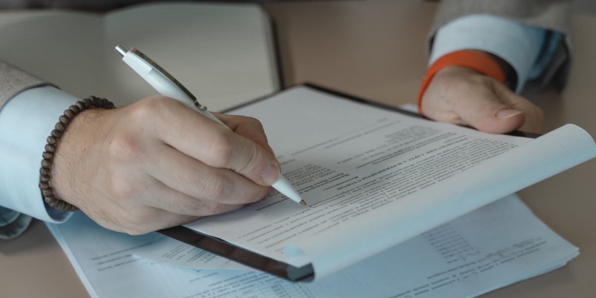 A person intently reviewing documents, symbolizing the careful consideration required for a smart real estate investment.