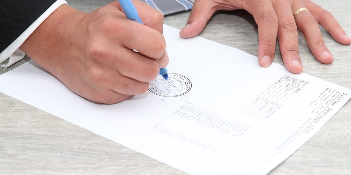 A person reviewing and signing important legal documents with a real estate consultant.
