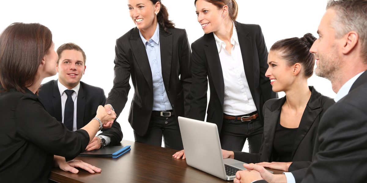 Two professionals shaking hands at a meeting table, symbolizing a successful negotiation and closing of a deal.